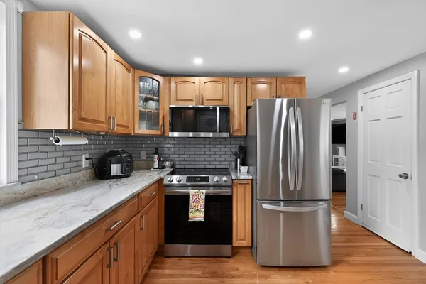 a kitchen with stainless steel appliances granite countertop a refrigerator a stove a sink and a microwave