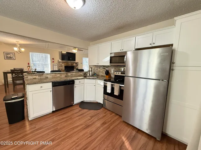 a kitchen with stainless steel appliances granite countertop a refrigerator a sink dishwasher a stove top oven a refrigerator with island and chairs
