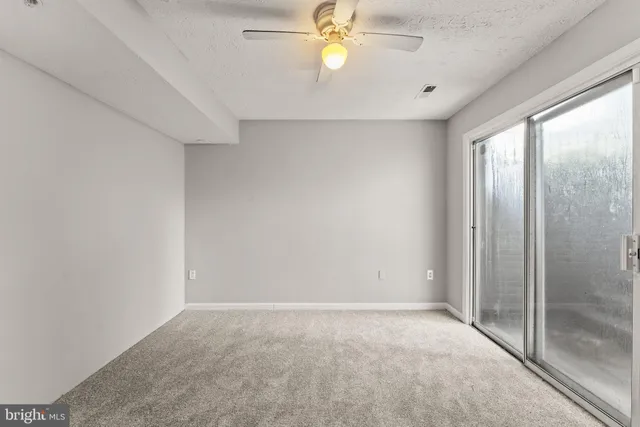 a view of an empty room with window and closet area