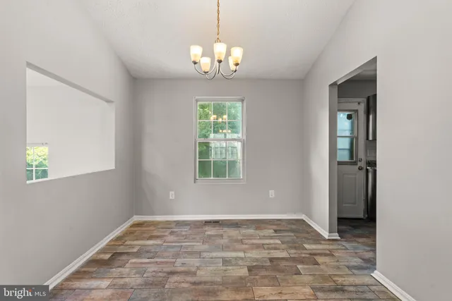 a view of an empty room with window and chandelier
