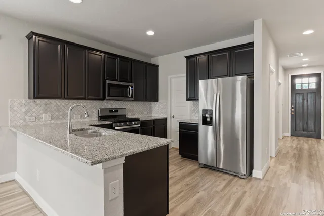 a kitchen with granite countertop wooden cabinets a refrigerator and a sink