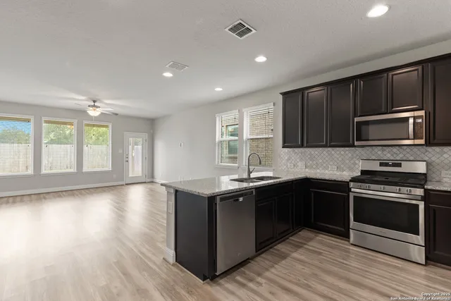a kitchen with stainless steel appliances granite countertop a stove a sink and a microwave