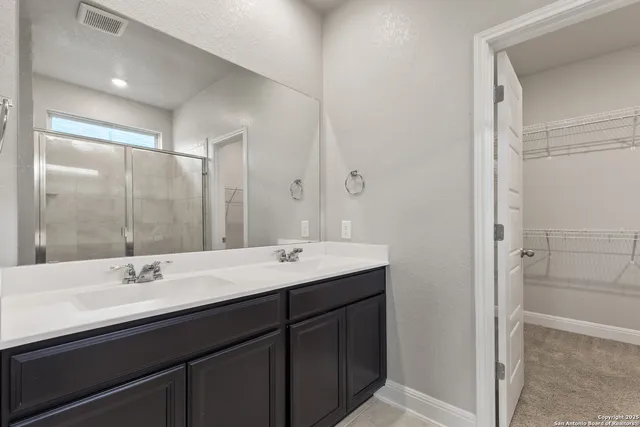 a bathroom with a double vanity sink mirror and shower