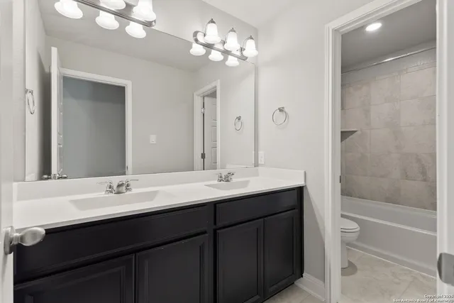 a bathroom with a sink double vanity granite tub and a mirror