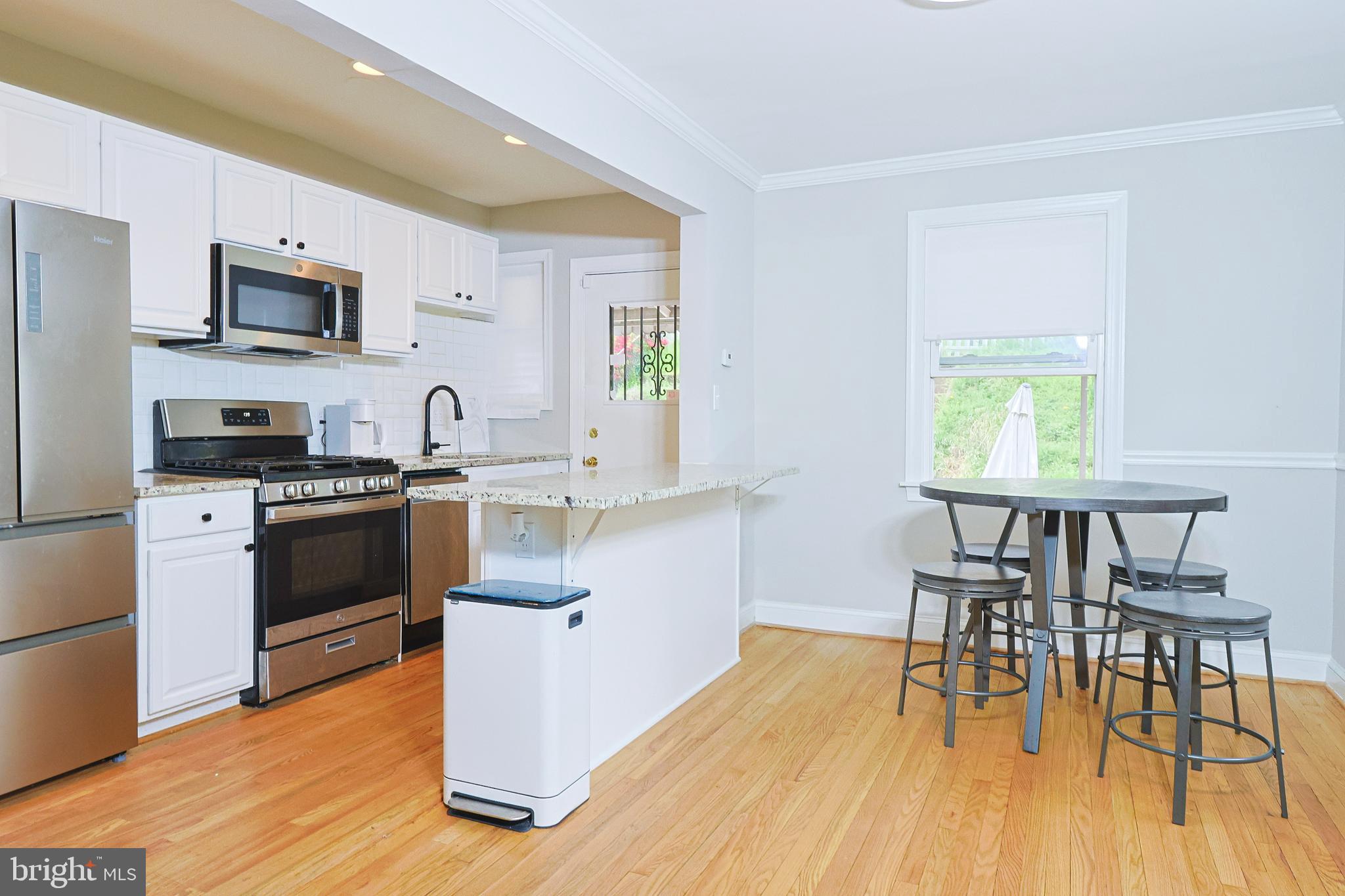 a kitchen with stainless steel appliances a stove a sink white cabinets and wooden floor