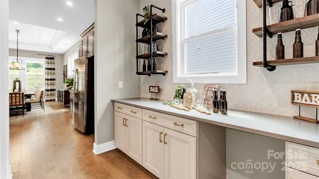 a kitchen with stainless steel appliances granite countertop a sink dishwasher and a refrigerator with wooden floor