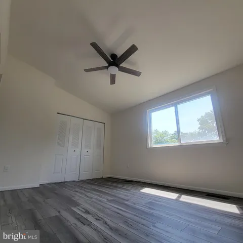 an empty room with wooden floor cabinet and windows