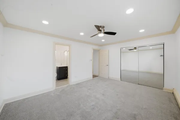 an empty room with ceiling fan and windows