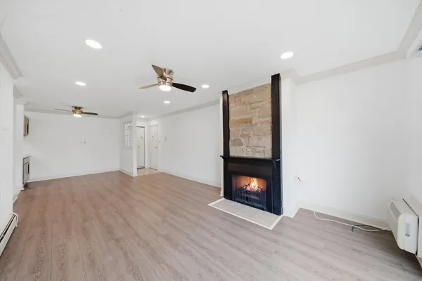 a view of an empty room with wooden floor fireplace and a window