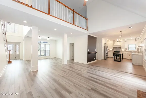 an empty room with wooden floor chandelier and windows