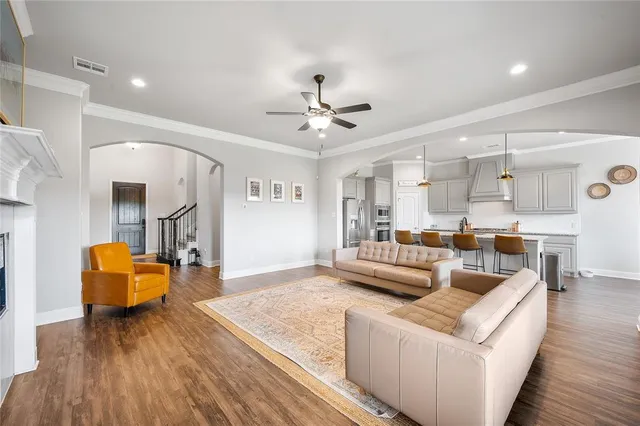 a kitchen with stainless steel appliances kitchen island granite countertop a refrigerator a oven a stove and white cabinets with wooden floor