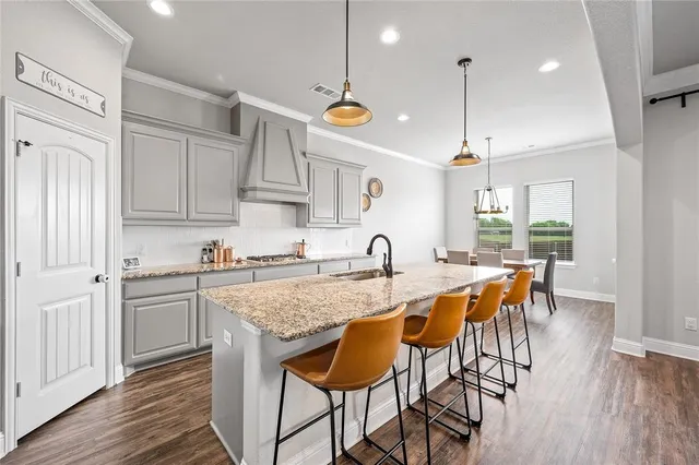 a kitchen with granite countertop a stove a sink a kitchen island with a dining table and chairs