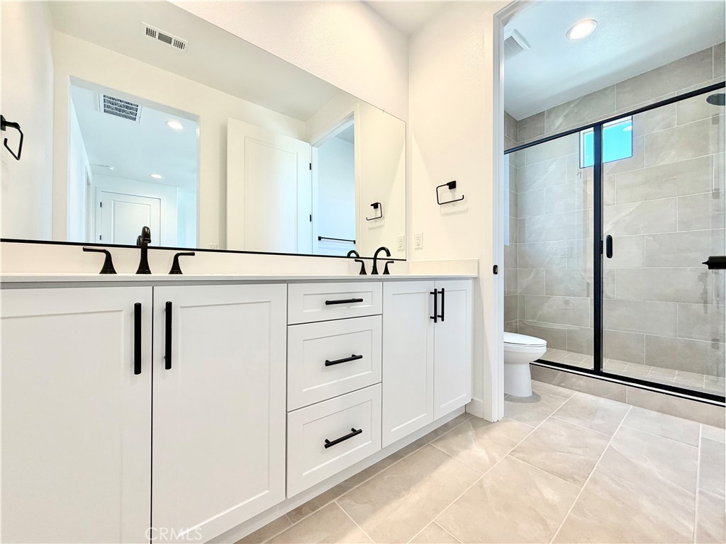 29561 Monarch Road Menifee, CA 92586 - Photo 18 of 35 a bathroom with a double vanity sink toilet mirror and shower