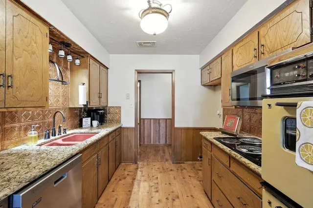 a kitchen with stainless steel appliances granite countertop a stove a sink and a microwave