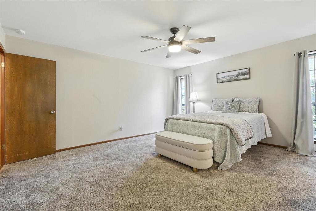 905 Clearview Drive Krum, TX 76249 - Photo 21 of 38 a spacious bedroom with a bed and a chandelier
