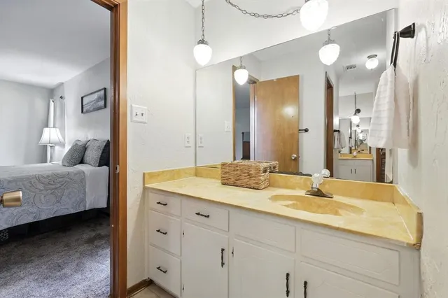 a en suite bathroom with a granite countertop double vanity sink and mirror