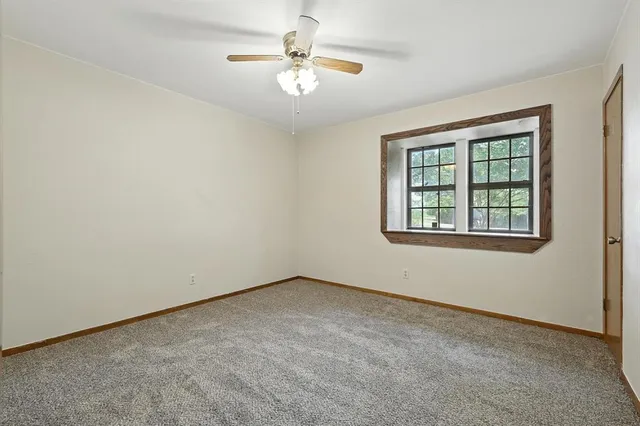 an empty room with a window and a ceiling fan