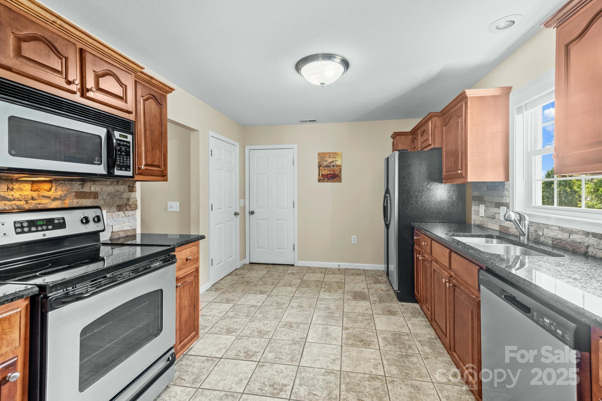 2133 Olde Farm Road Southeast Hudson, NC 28638 - Photo 11 of 42 a kitchen with stainless steel appliances granite countertop a stove top oven a sink and a refrigerator