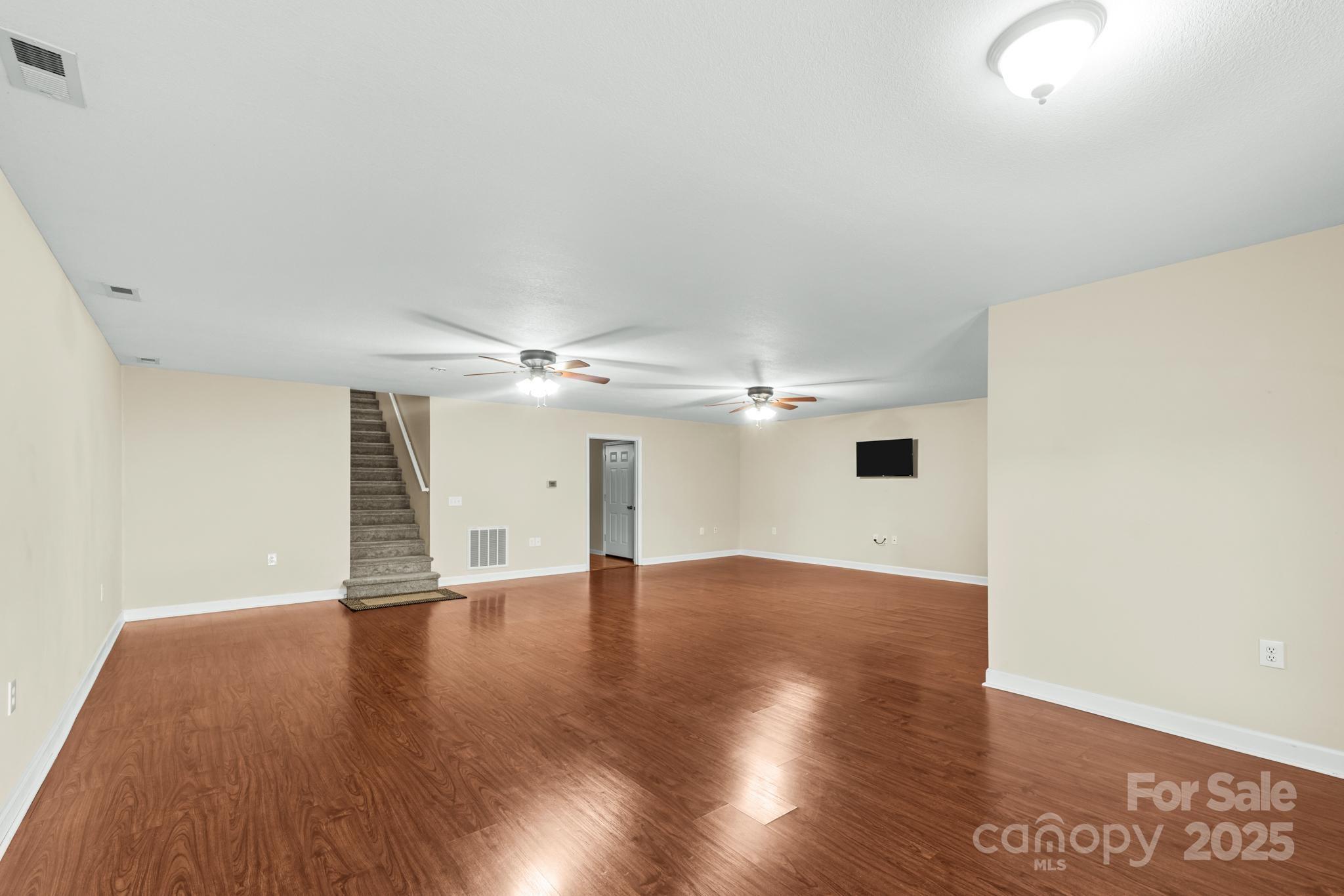 2133 Olde Farm Road Southeast Hudson, NC 28638 - Photo 15 of 42 an empty room with wooden floor chandelier fan and windows