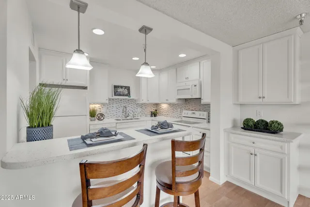 a kitchen with stainless steel appliances kitchen island granite countertop a stove a sink a refrigerator and white cabinets with wooden floor