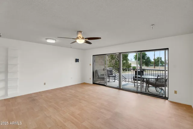 an empty room with window and ceiling fan