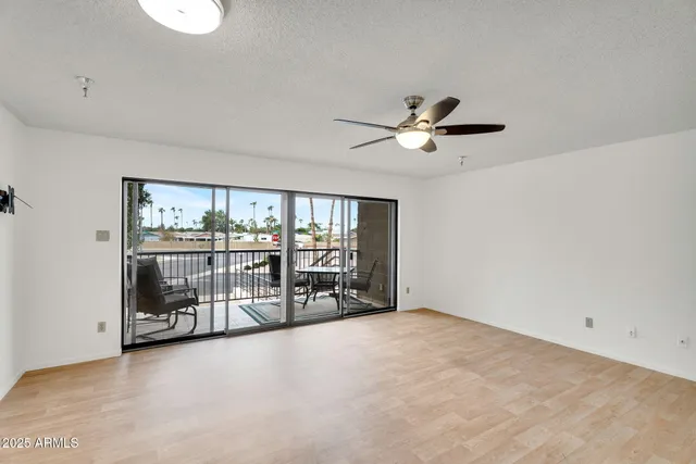 an empty room with chandelier fan and windows