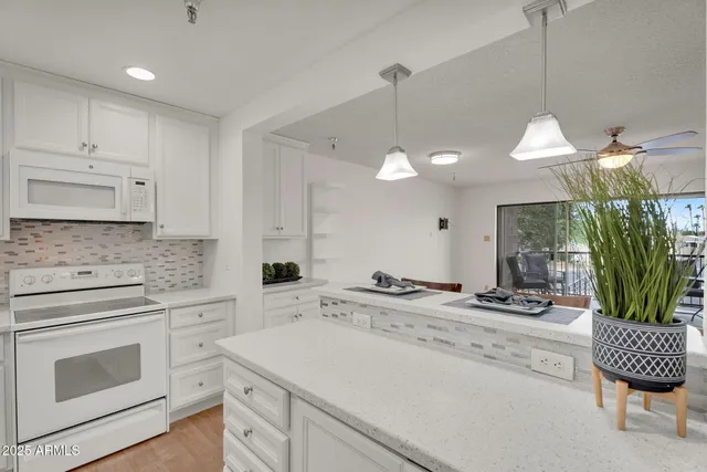 a kitchen with granite countertop white cabinets and white appliances