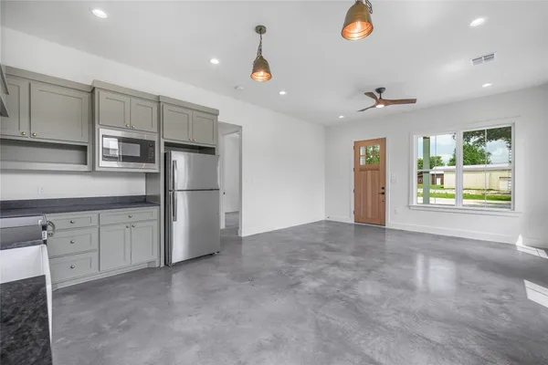 a view of cabinets stainless steel appliances wooden floor and a window