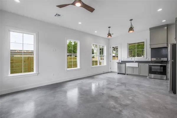 a view of an empty room with a window and kitchen view