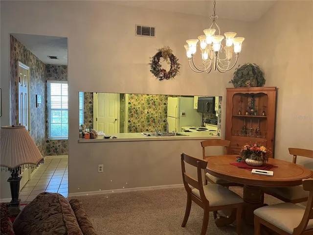 a view of a dining room with furniture a chandelier and a window