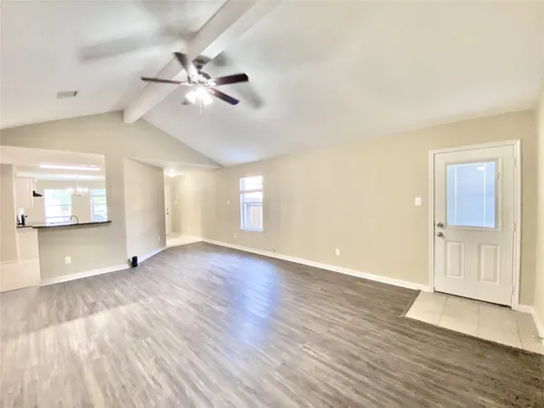 a view of an empty room with window and wooden floor