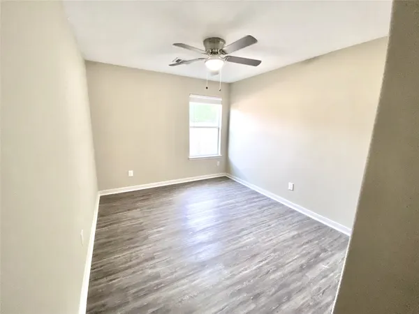 a view of a room with wooden floor and a ceiling fan