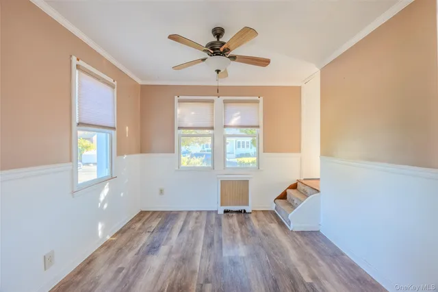 an empty room with wooden floor a ceiling fan and windows