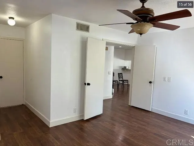 a view of a livingroom with wooden floor a ceiling fan and staircase