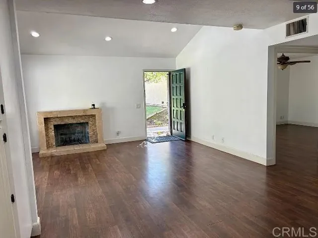 an empty room with wooden floor and fireplace