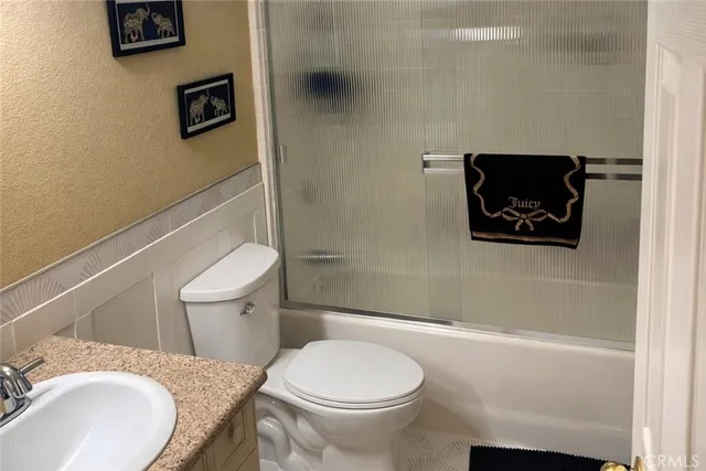a bathroom with a granite countertop toilet and a sink
