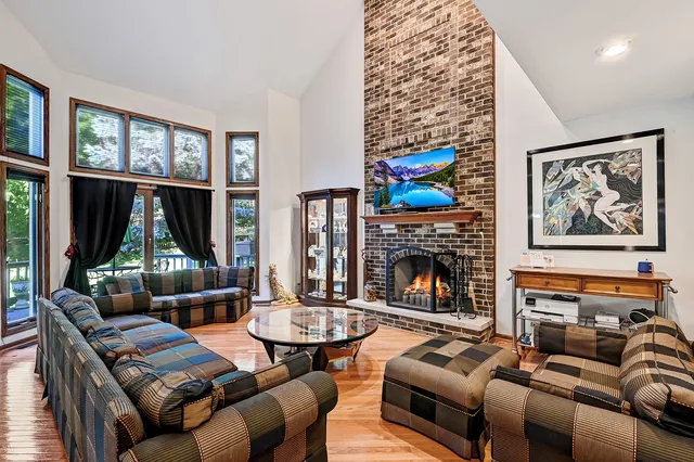 a living room with furniture a fireplace and a floor to ceiling window