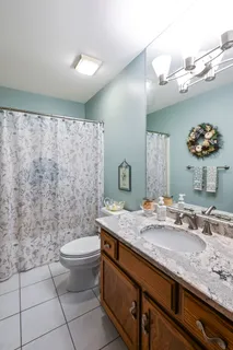 a bathroom with a granite countertop sink a toilet and a mirror