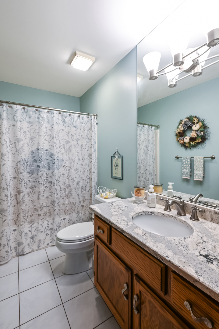 8826 Carlisle Court Darien, IL 60561 - Photo 15 of 36 a bathroom with a granite countertop sink a toilet and a mirror