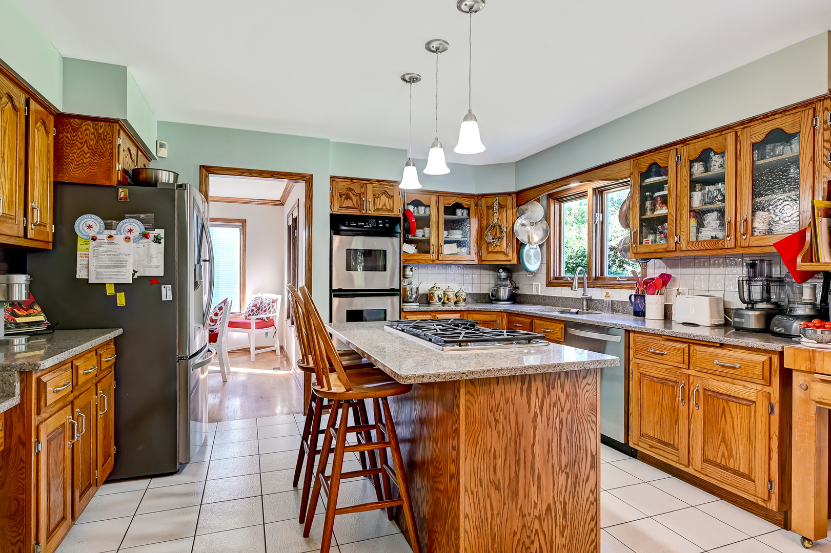 8826 Carlisle Court Darien, IL 60561 - Photo 8 of 36 a kitchen with stainless steel appliances granite countertop a stove top oven a refrigerator a sink dishwasher and a dining table with the living room view
