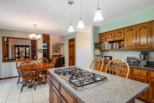 a kitchen with stainless steel appliances granite countertop a stove a sink a dining table and chairs with wooden floor