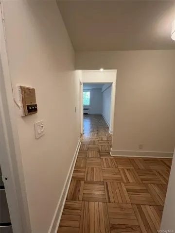 a view of a hallway with wooden floor and a bathroom