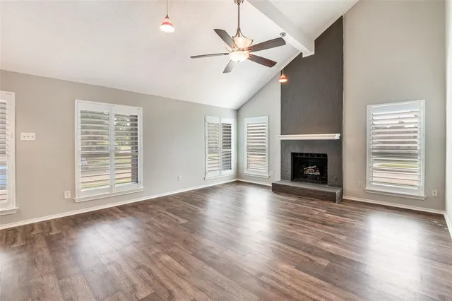 an empty room with wooden floor fireplace and windows