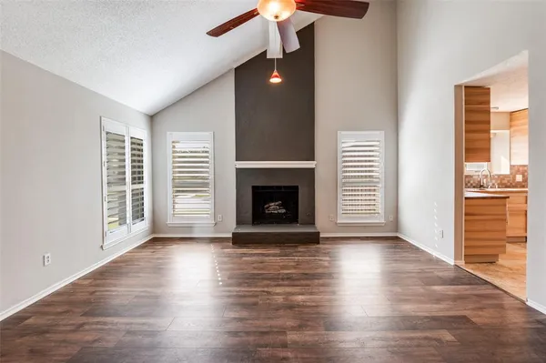 a view of an empty room with wooden floor fireplace and a window
