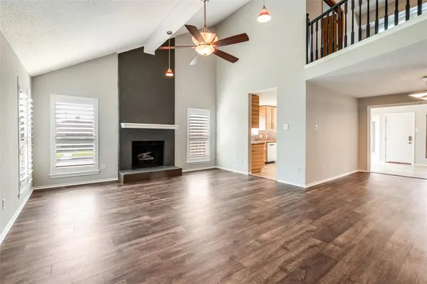an empty room with wooden floor fireplace and windows
