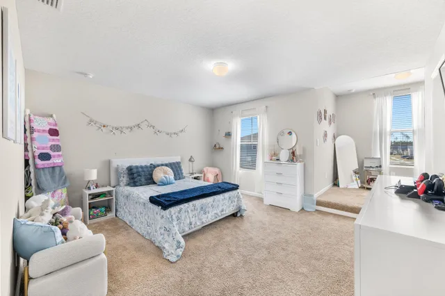a spacious bedroom with a bed a table and window