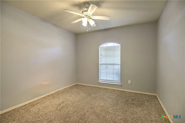 an empty room with windows and ceiling fan