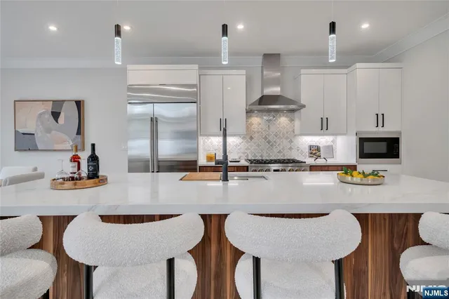 a kitchen with stainless steel appliances granite countertop a table chairs stove and kitchen island