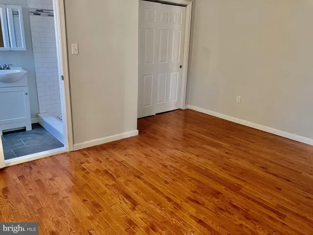 a view of an empty room with wooden floor and a sink
