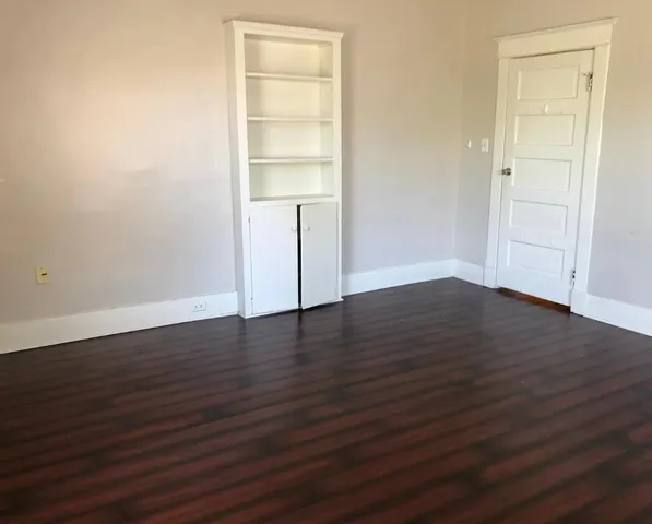 an empty room with wooden floor & closet area